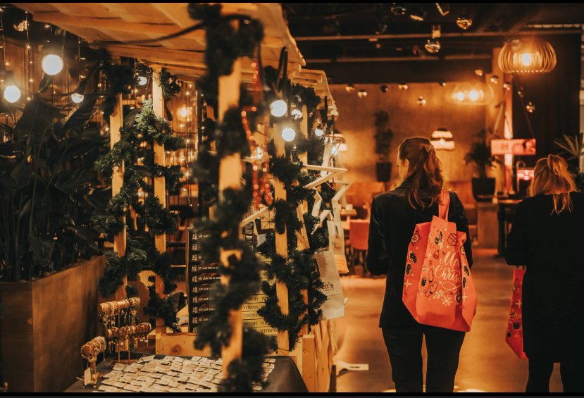 Medewerkers met kersttas lopen langs de kraampjes van de kerstmarkt