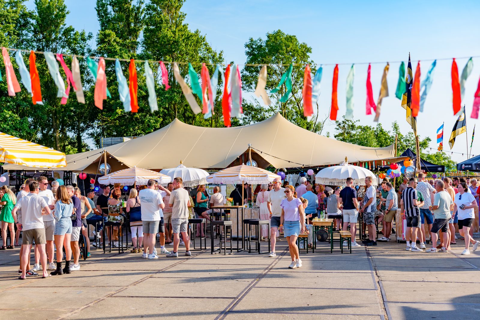 Outdoor party with stretch tent, parasols, high tables and bunting