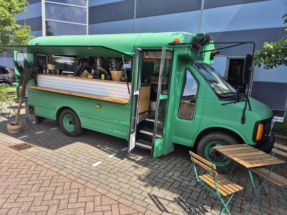 Green American school bus with open awning and terrace